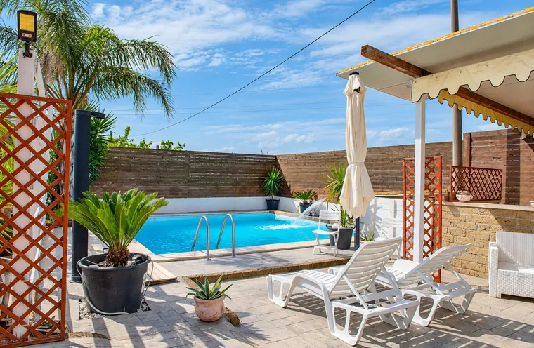 La piscina con il pergolato, l'ombrellone e i lettini